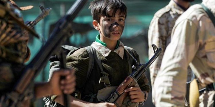A Yemeni child drafted by Houthi militias carrying a weapon (AFP)