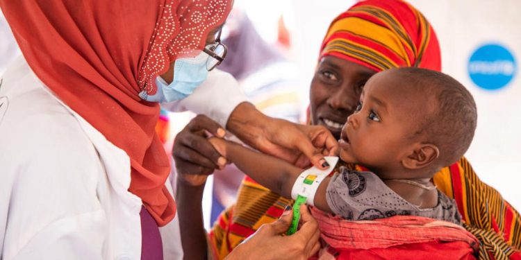 A health worker at a site for internally-displaced persons in Ethiopia measures the arm of a child to assess his nutrition status.
